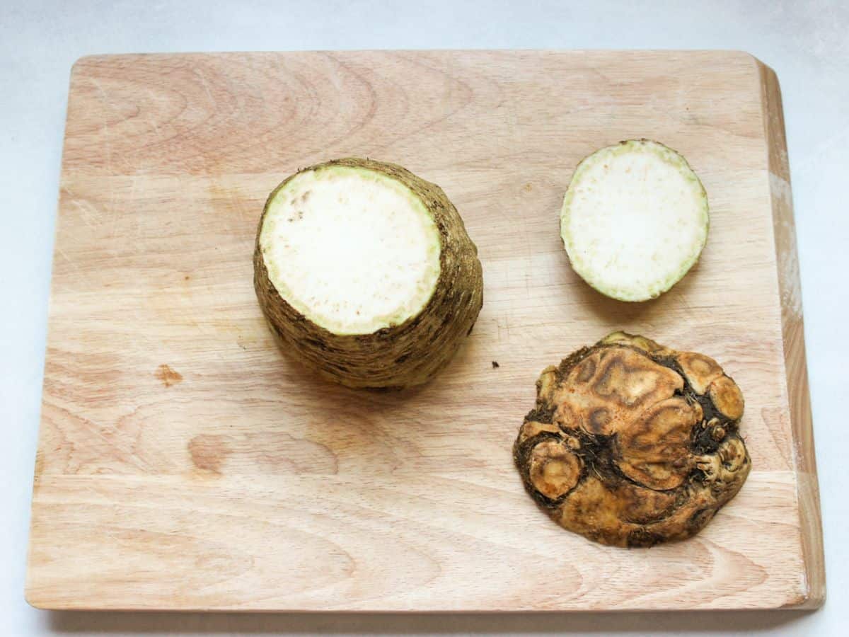 A large root with its tops cut off on a wooden cutting board.