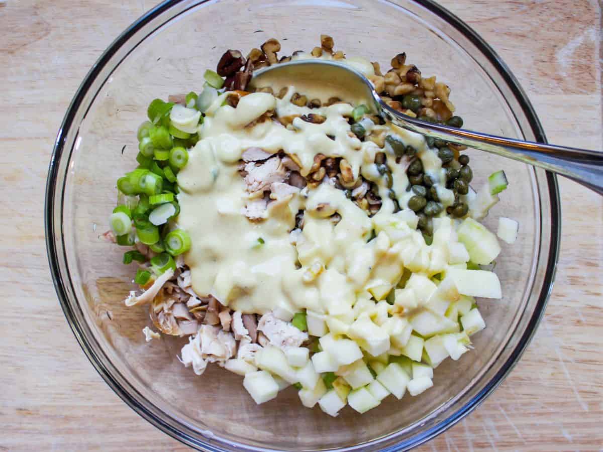 Unmixed chicken salad topped with mayo dressing without salary in a glass bowl