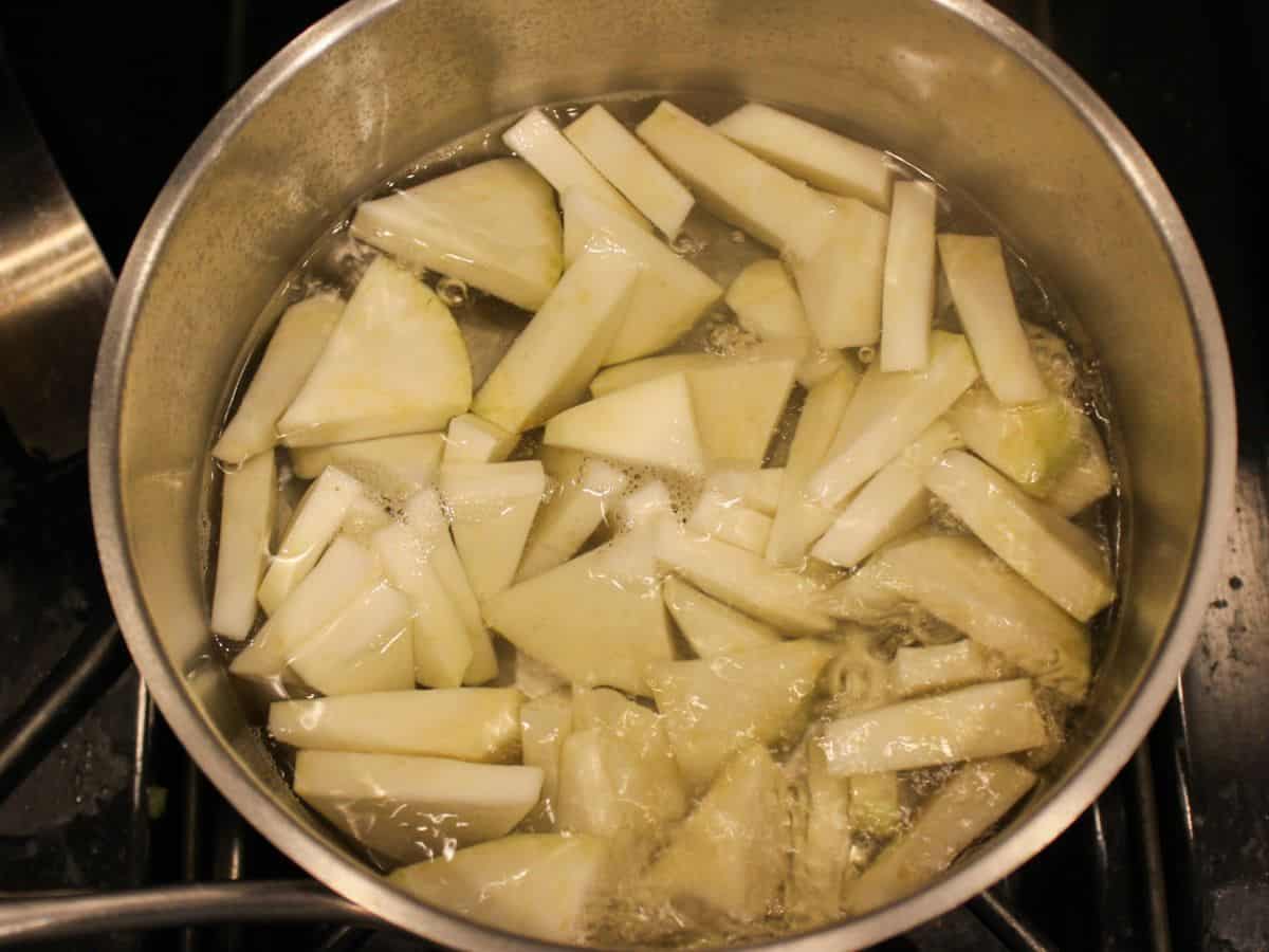 Sliced celery root in a pot with boiling water.