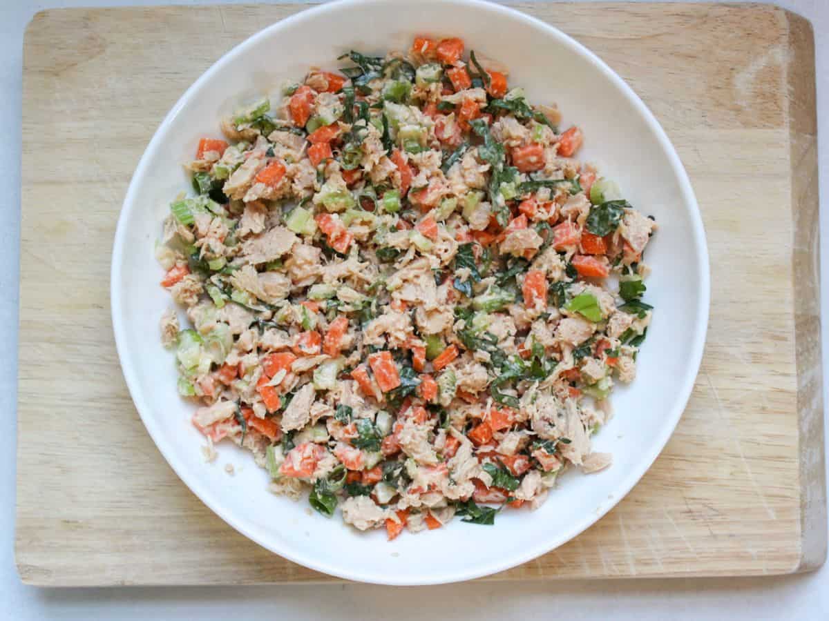 Tuna salad with carrots, celery and green onions in a shallow white dish.