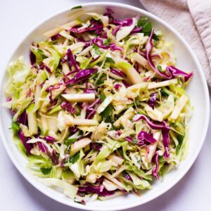 Cabbage and apple salad in a white shallow dish.