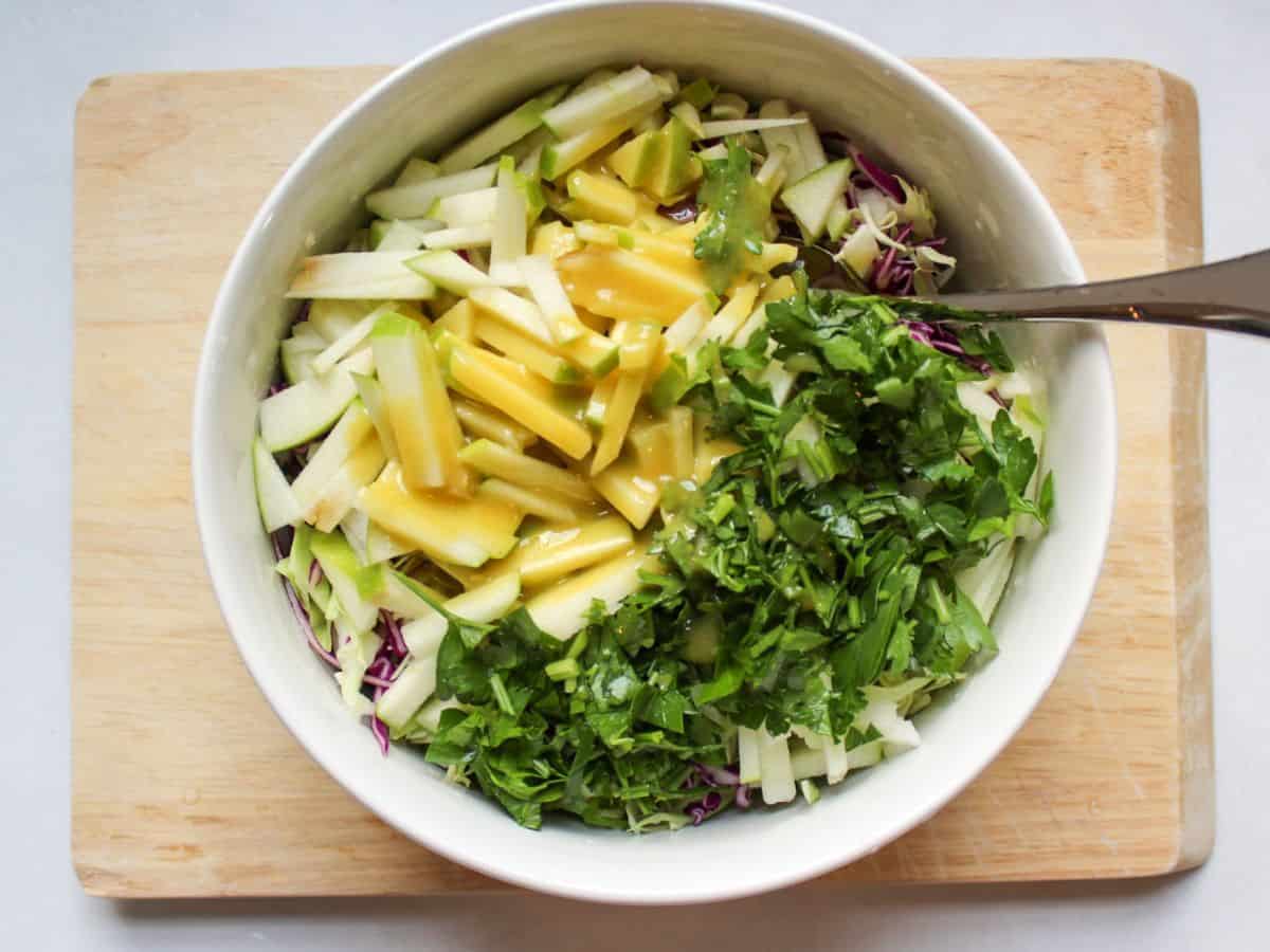 All salad ingredients drizzled with the dressing in a large white bowl.