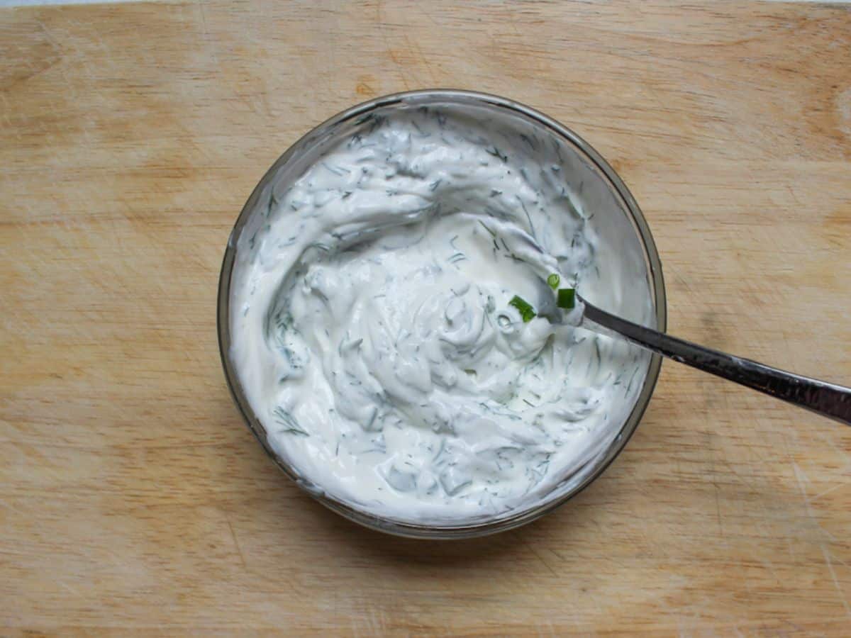 Sour cream dressing mixed in a glass small bowl with a fork in it.
