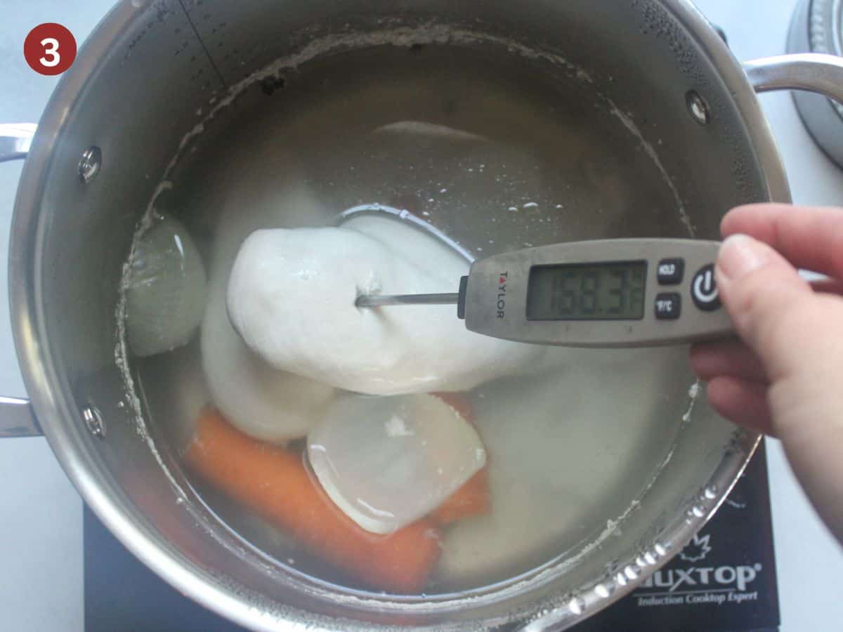 Meat thermometer inserted into poached chicken breast.